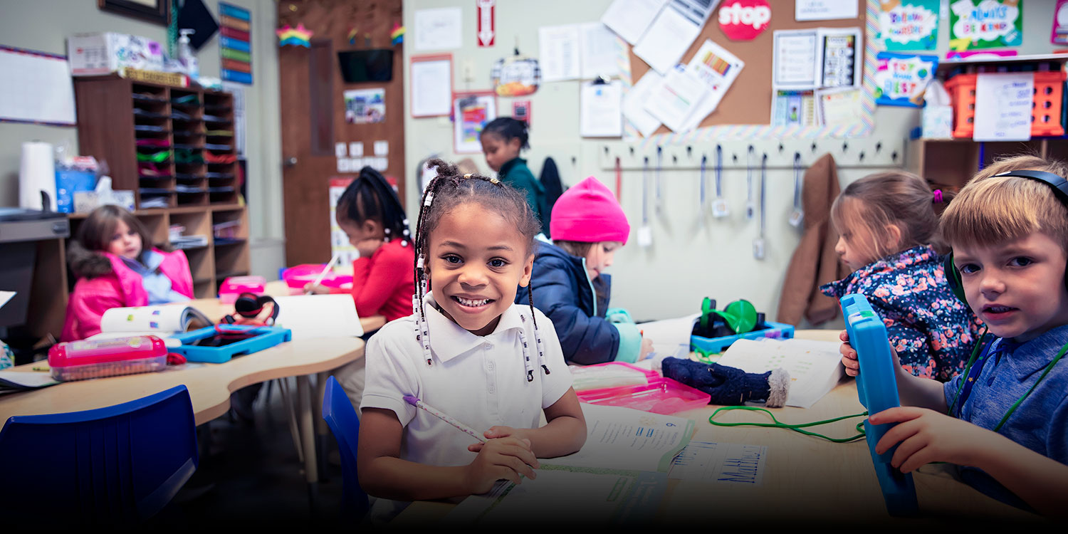 Smiling children at desks in their classroom.